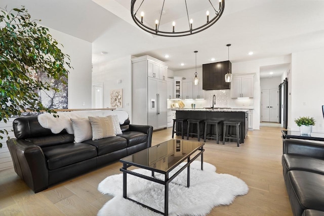 living room with light wood-style floors, an inviting chandelier, and recessed lighting