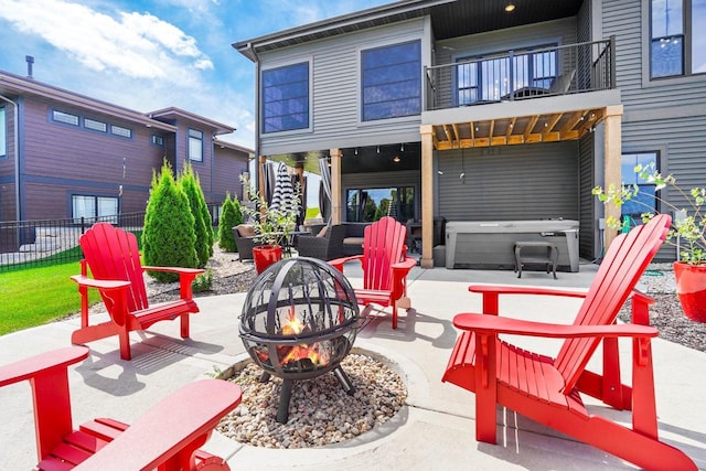 view of patio with stairway, a hot tub, an outdoor fire pit, fence, and a balcony