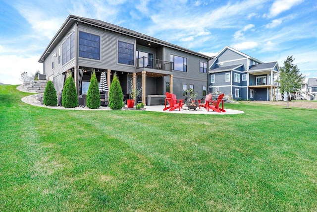 rear view of house with a yard, an outdoor fire pit, a patio area, and a balcony