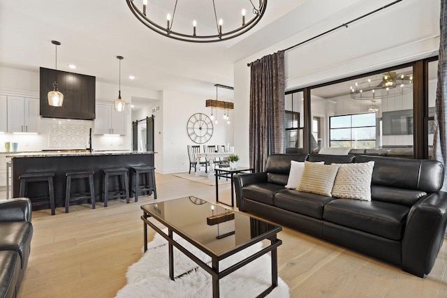 living room with recessed lighting, light wood finished floors, and an inviting chandelier