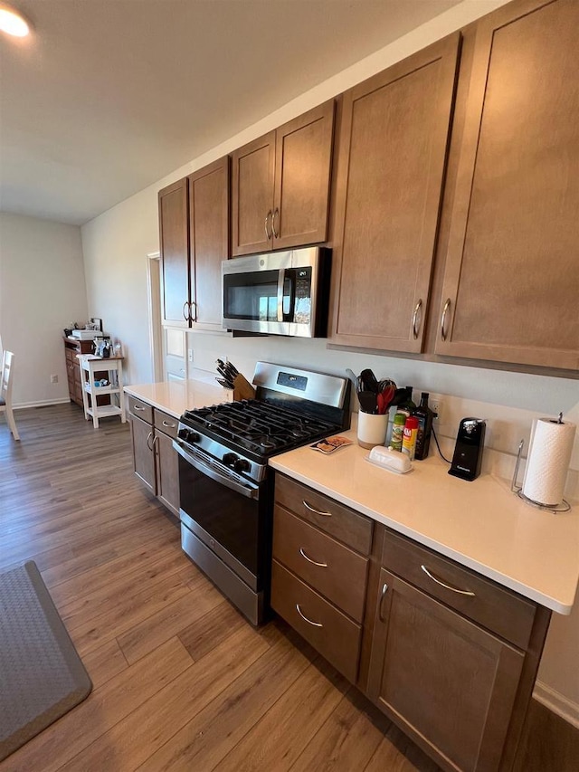 kitchen featuring appliances with stainless steel finishes, light countertops, baseboards, and wood finished floors