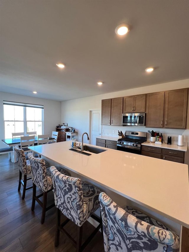 kitchen featuring dark wood finished floors, a breakfast bar area, recessed lighting, appliances with stainless steel finishes, and a sink