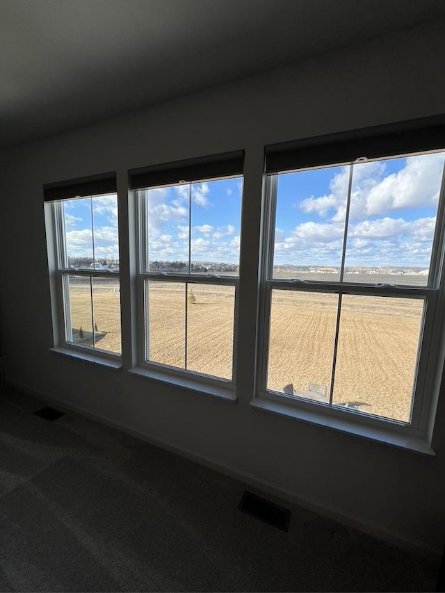 empty room with carpet, visible vents, and baseboards