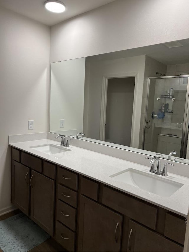 full bath with a stall shower, a sink, and double vanity