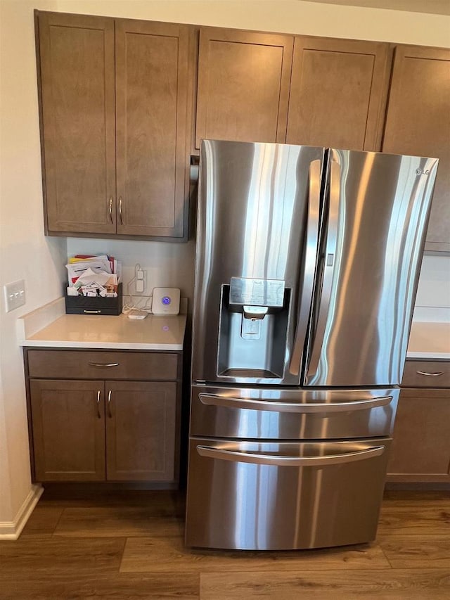 kitchen featuring light countertops, stainless steel fridge, and wood finished floors