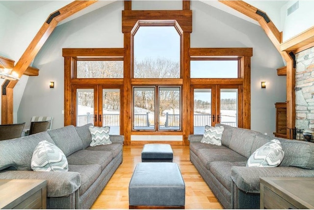 living area featuring light wood finished floors, french doors, and a high ceiling