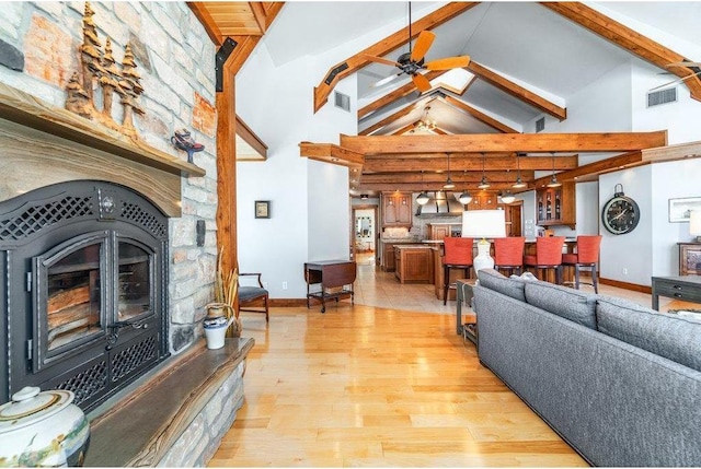 living room featuring light wood finished floors, beam ceiling, visible vents, and a ceiling fan