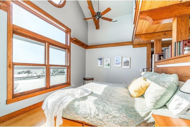 bedroom featuring lofted ceiling, baseboards, visible vents, and wood finished floors