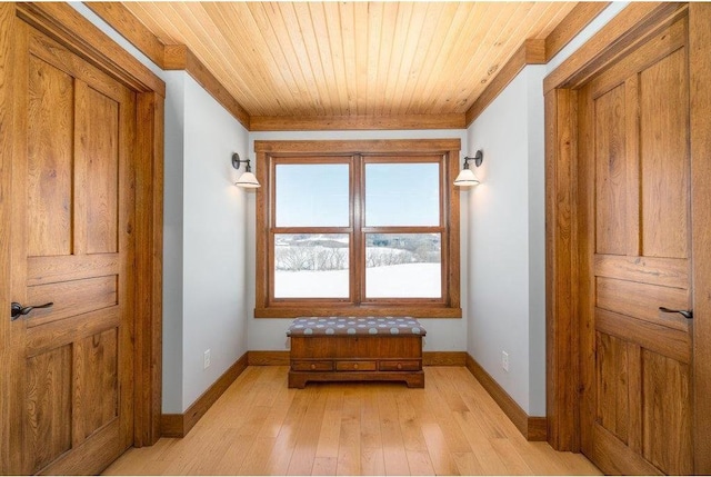 corridor with baseboards, light wood finished floors, wooden ceiling, and crown molding