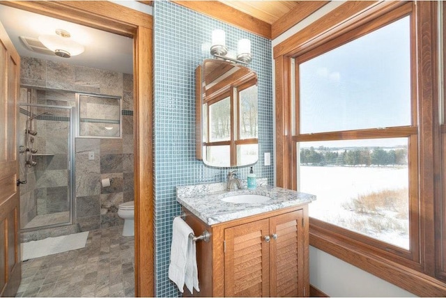 bathroom featuring toilet, a shower stall, tile walls, and vanity