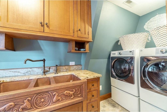 clothes washing area featuring visible vents, cabinet space, a sink, and washing machine and clothes dryer