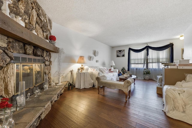 bedroom with a textured ceiling, dark wood-type flooring, and a fireplace