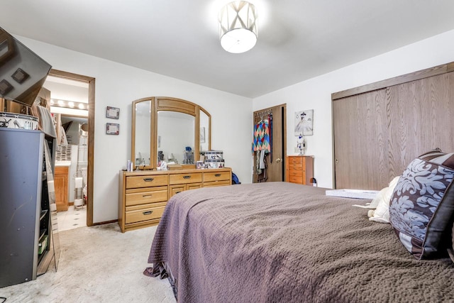 bedroom featuring ensuite bathroom, two closets, and light colored carpet