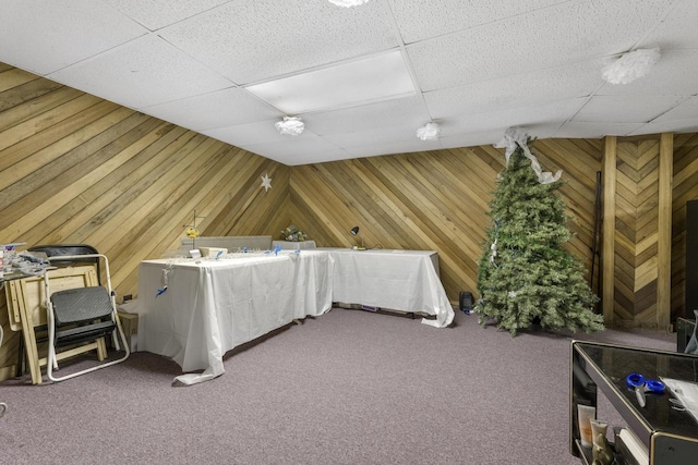 misc room with carpet floors, wood walls, and a paneled ceiling