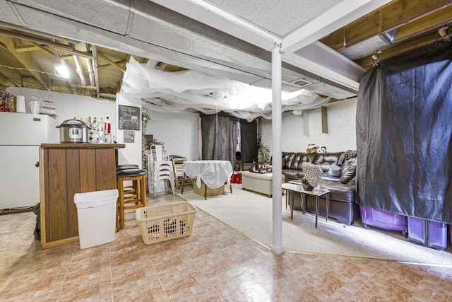 unfinished basement featuring freestanding refrigerator