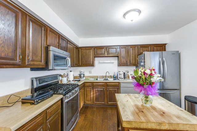 kitchen with light countertops, appliances with stainless steel finishes, dark wood-style flooring, and a sink