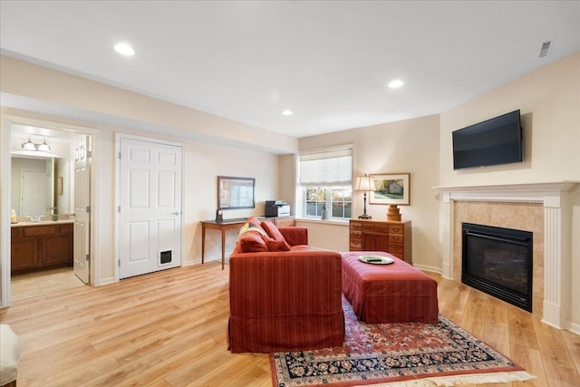 living room with baseboards, recessed lighting, a tiled fireplace, and light wood-style floors