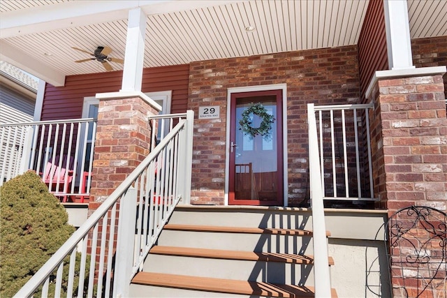 property entrance featuring ceiling fan, brick siding, and a porch