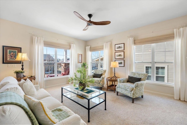 carpeted living area with ceiling fan and baseboards