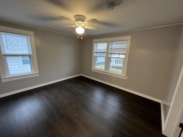 spare room featuring ceiling fan, crown molding, dark wood-style flooring, and baseboards