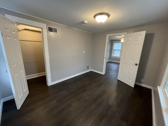 unfurnished bedroom featuring dark wood-type flooring, visible vents, and baseboards