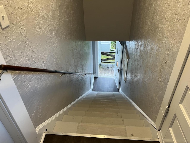 staircase with baseboards and a textured wall