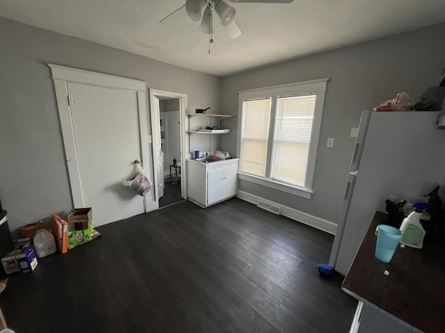 interior space with dark wood-style floors, visible vents, baseboards, and a ceiling fan