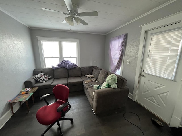 living area featuring ceiling fan, a textured wall, ornamental molding, and baseboards