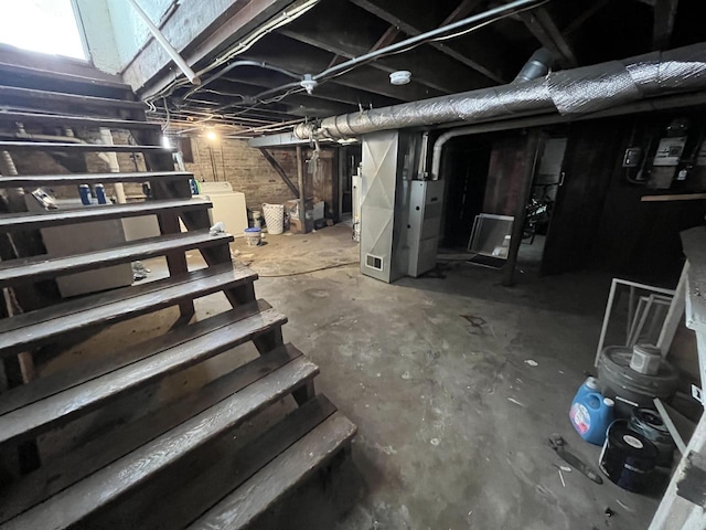 unfinished basement with washer / dryer and heating unit