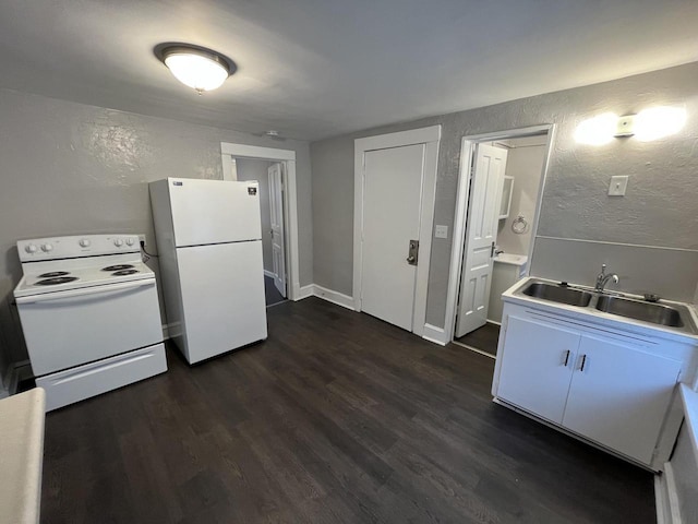 kitchen with a textured wall, dark wood finished floors, white appliances, and a sink