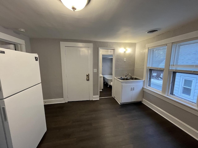 kitchen with baseboards, visible vents, dark wood-style flooring, freestanding refrigerator, and a sink