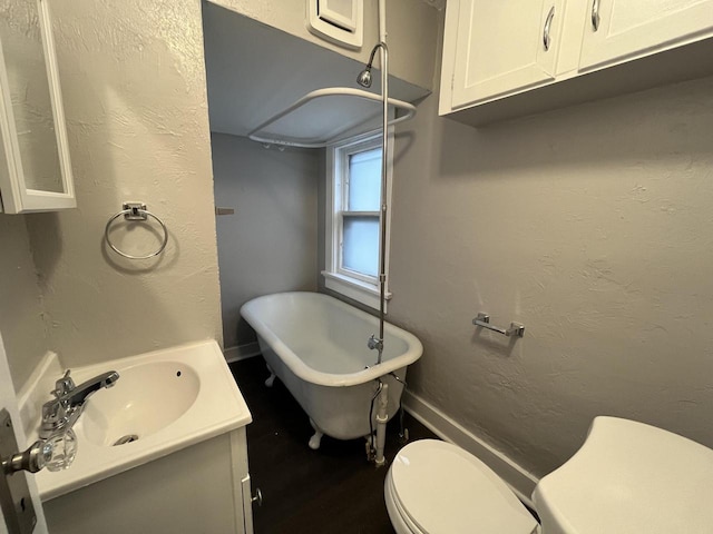 full bath with a textured wall, a freestanding bath, vanity, and toilet