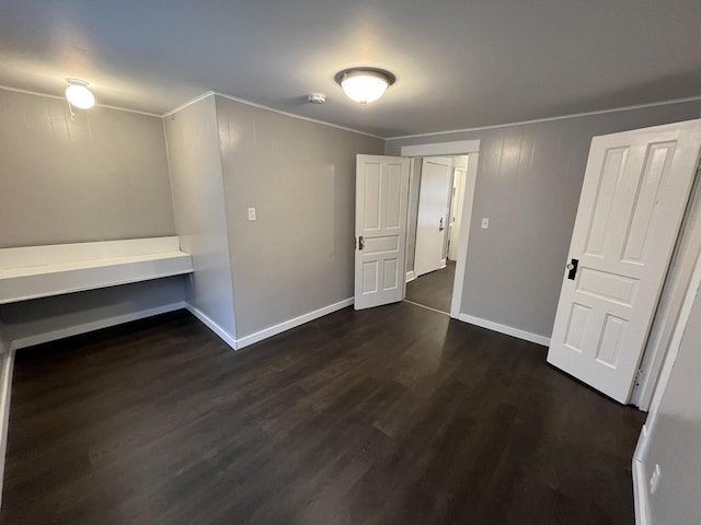 unfurnished bedroom featuring ornamental molding, dark wood-type flooring, and baseboards