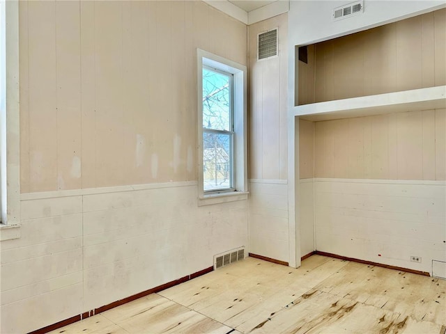 empty room featuring visible vents and wood walls