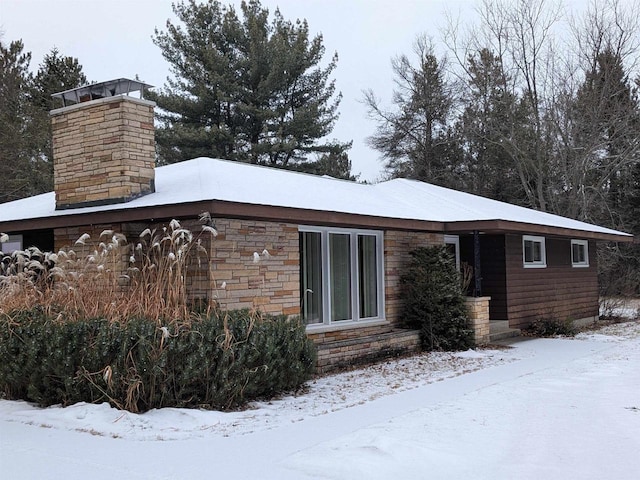 view of front of home with stone siding and a chimney