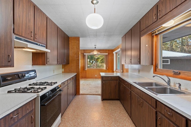 kitchen featuring under cabinet range hood, a sink, light countertops, light floors, and range with gas cooktop