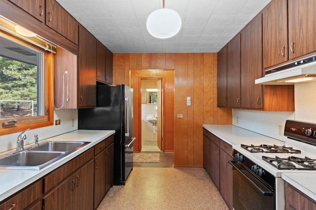 kitchen with under cabinet range hood, a sink, range with gas stovetop, light countertops, and light floors