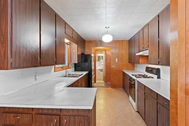 kitchen featuring gas range gas stove, light floors, light countertops, a sink, and under cabinet range hood