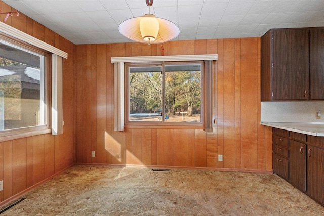 unfurnished dining area with wood walls, carpet, and visible vents