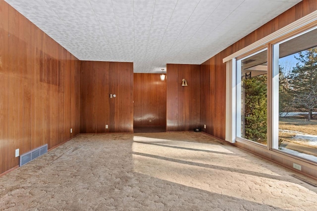 spare room featuring wood walls, visible vents, and a healthy amount of sunlight