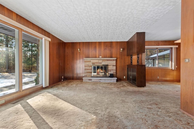 unfurnished living room featuring carpet floors, a fireplace, and wood walls