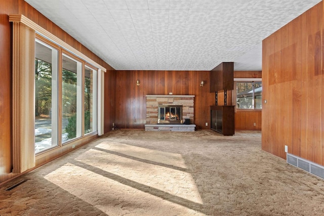 unfurnished living room featuring visible vents, wood walls, and carpet flooring