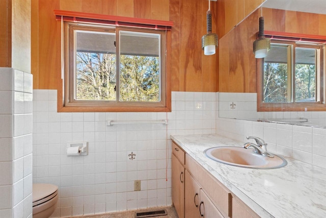 bathroom featuring tile walls, visible vents, vanity, and toilet