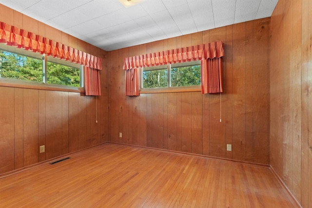 empty room with plenty of natural light, visible vents, and hardwood / wood-style floors