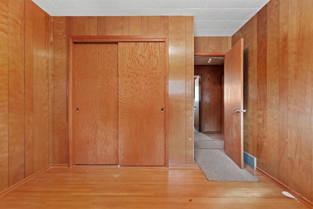 interior space with a closet, wooden walls, and wood finished floors