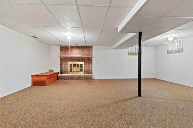 below grade area featuring concrete block wall, a brick fireplace, carpet, and a paneled ceiling