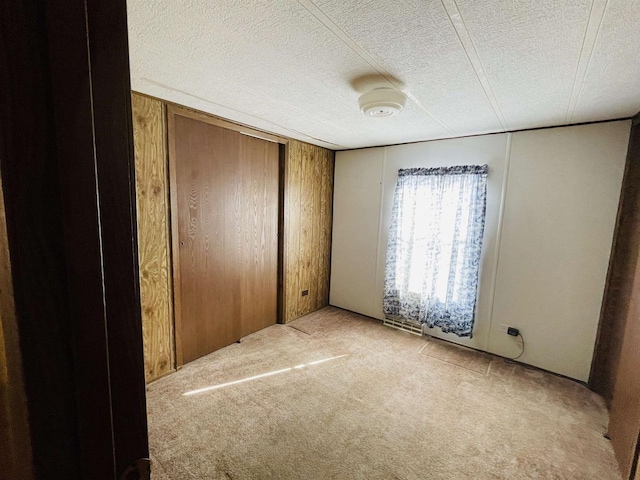 unfurnished bedroom featuring light carpet, a closet, and a textured ceiling