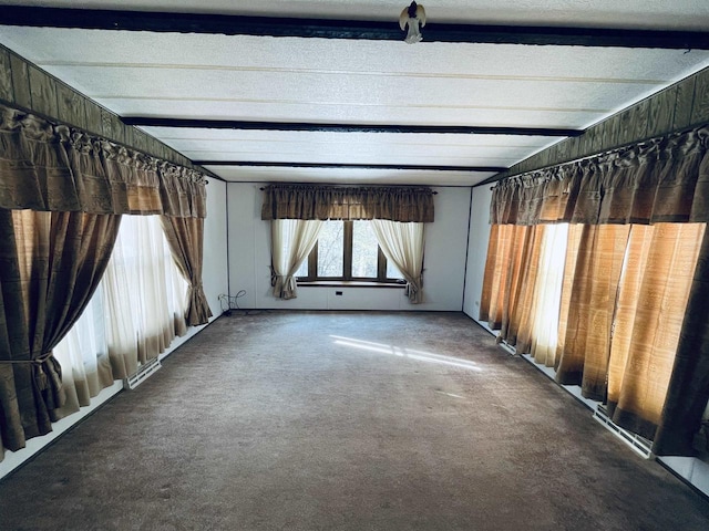 spare room featuring wood walls, carpet, and beamed ceiling