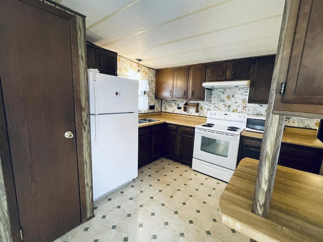 kitchen featuring under cabinet range hood, white appliances, a sink, light countertops, and light floors