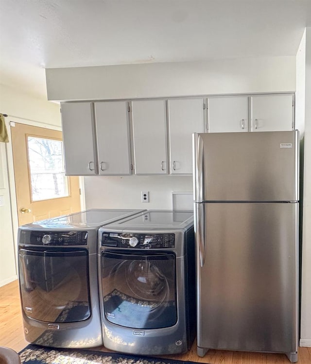 kitchen featuring light wood finished floors, gray cabinets, freestanding refrigerator, and washing machine and clothes dryer